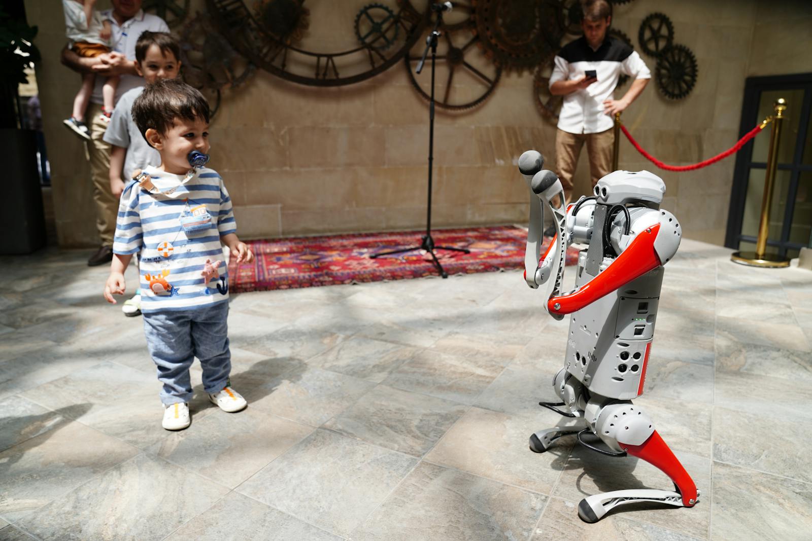 A young boy engages with a humanoid robot during an indoor tech exhibition, symbolizing future innovation.